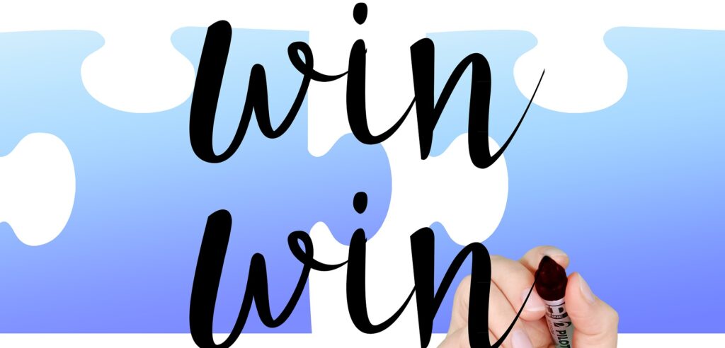 Hand writing the words 'win win' with a black marker. There is a blue and white background.
