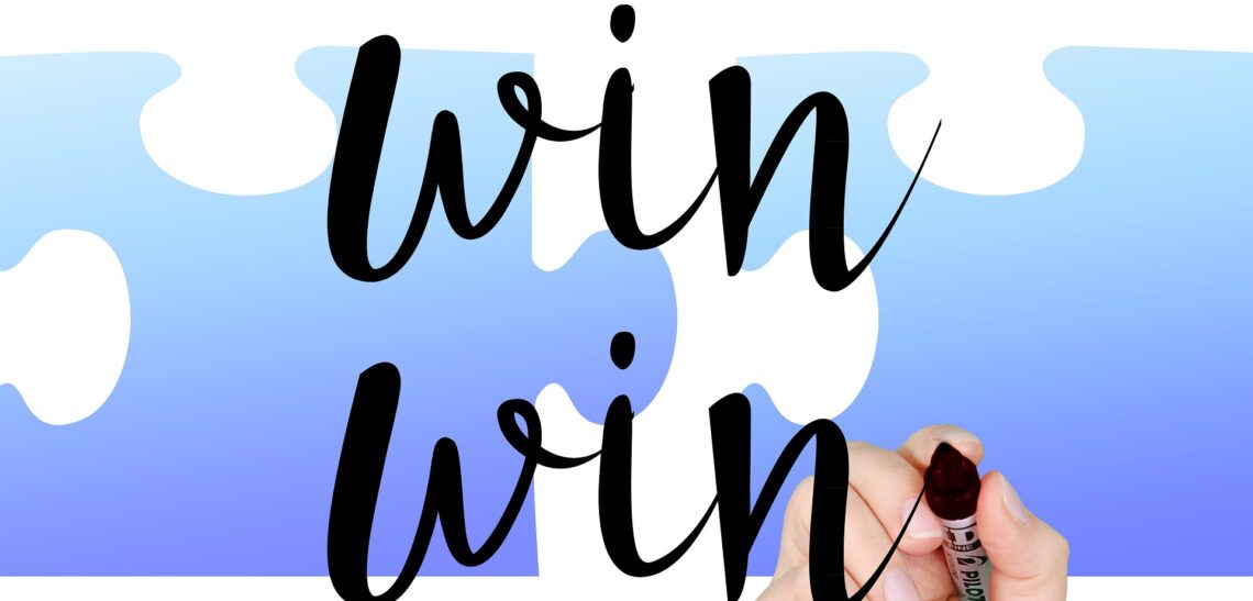 Hand writing the words 'win win' with a black marker. There is a blue and white background.