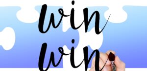 Hand writing the words 'win win' with a black marker. There is a blue and white background.